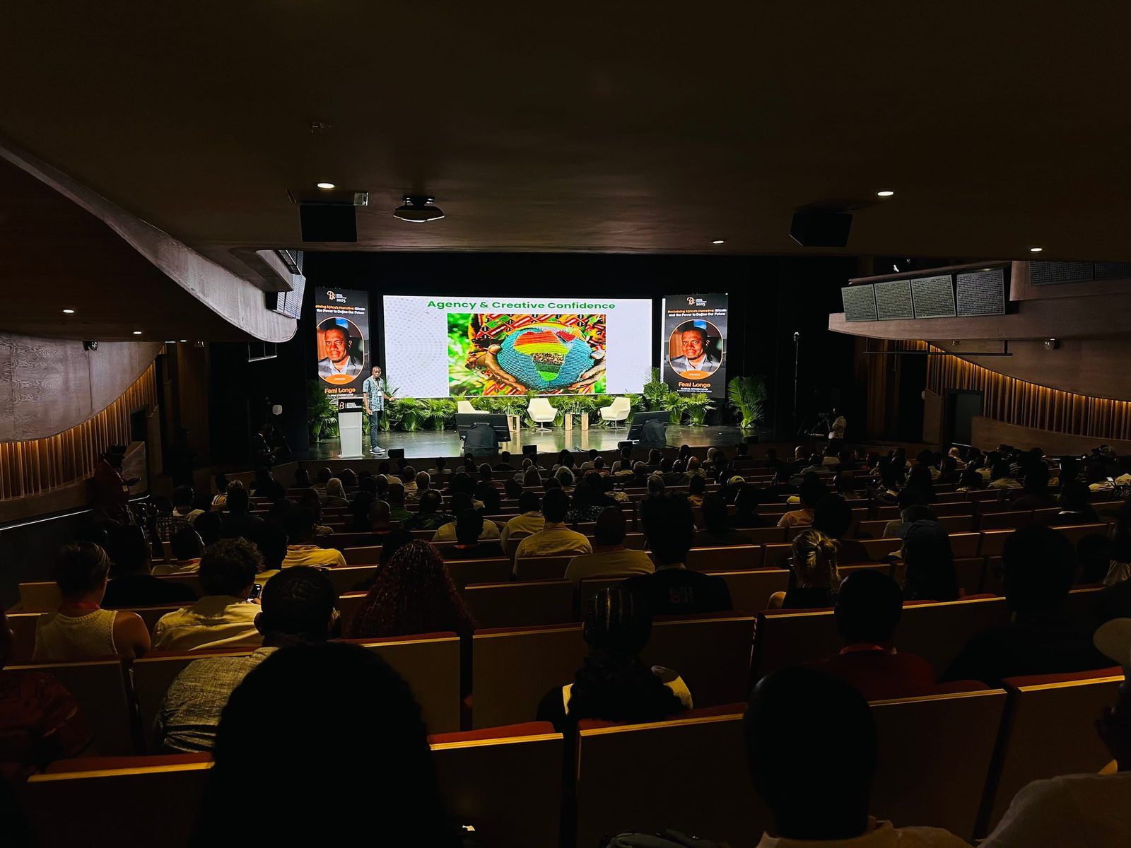 The Africa Bitcoin Conference auditorium in Port Louis from the back rows, a speaker at the lectern and the hall full.