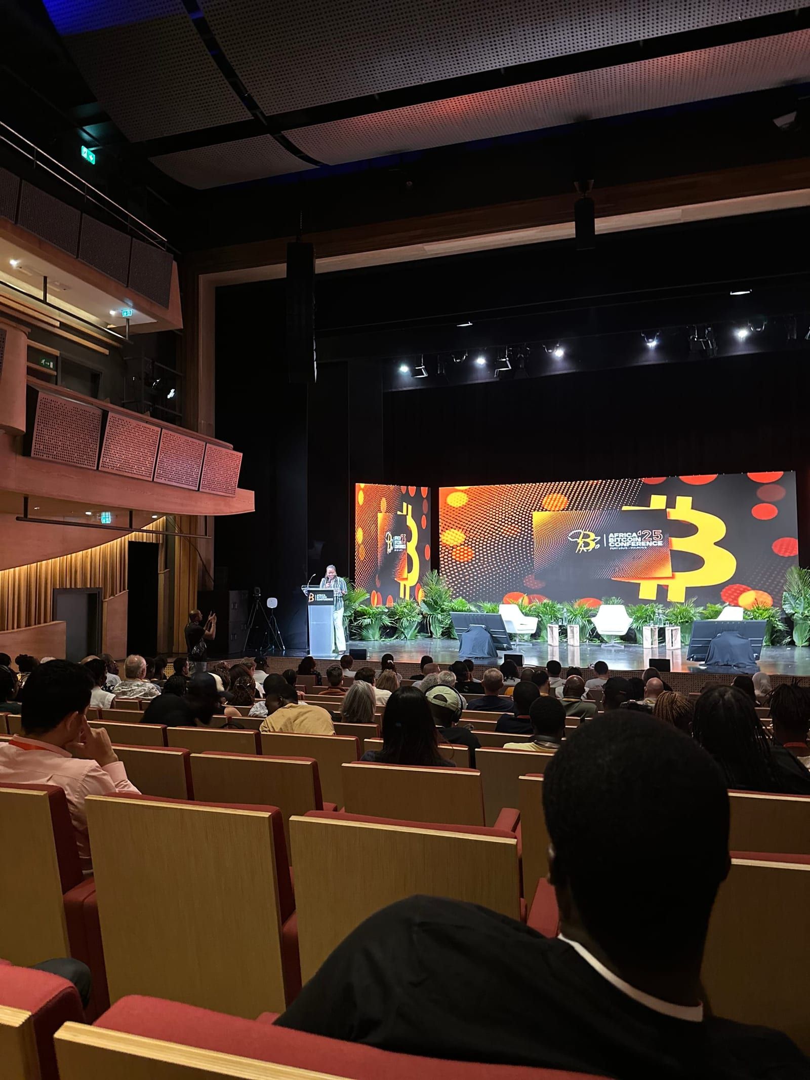 The Africa Bitcoin Conference main stage seen from the audience, a large orange Bitcoin mark on the LED wall.