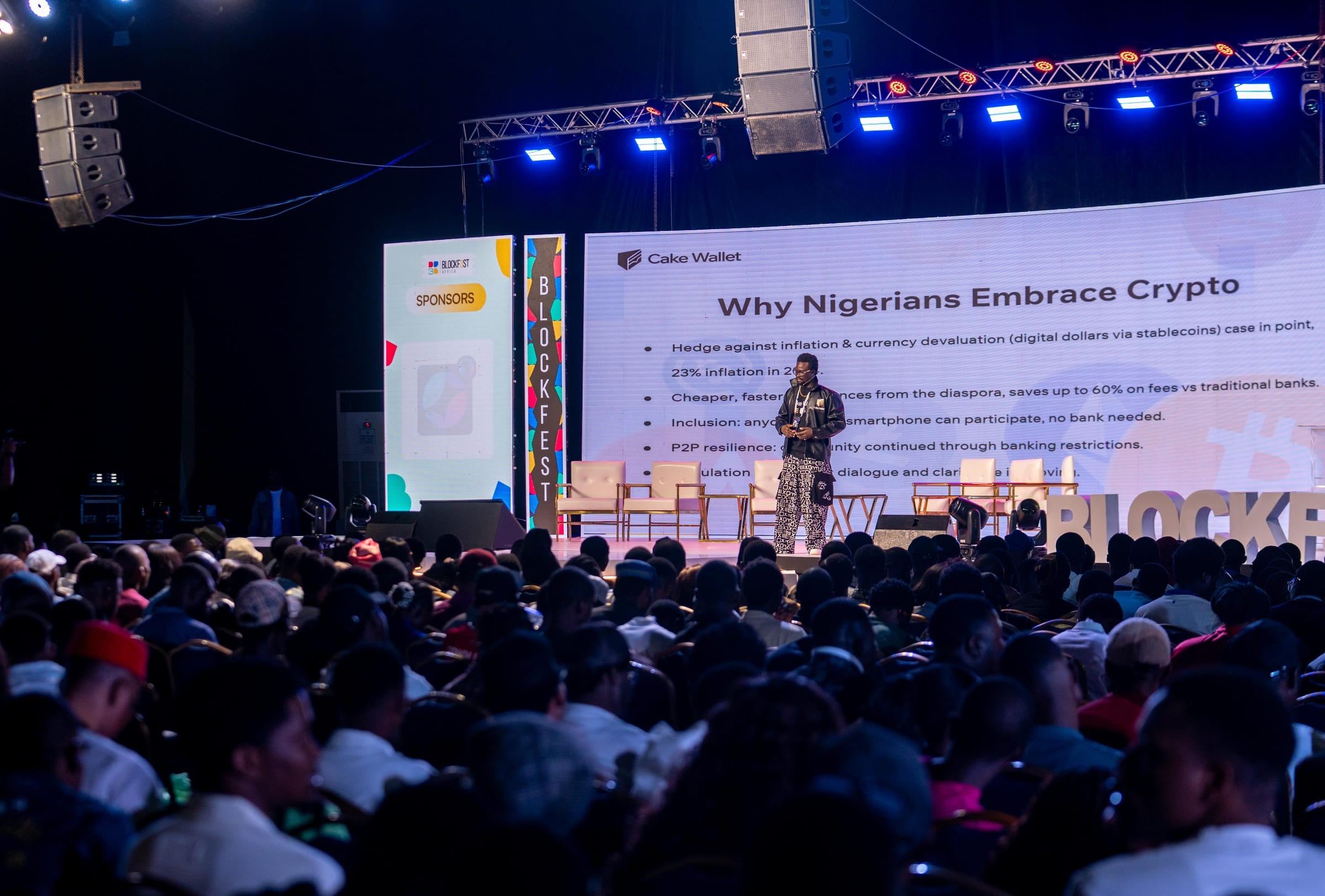 David Adegoke on the main stage at Blockfest Africa 2025 in Lagos, speaking to a packed hall, with a Cake Wallet slide reading Why Nigerians Embrace Crypto behind him.