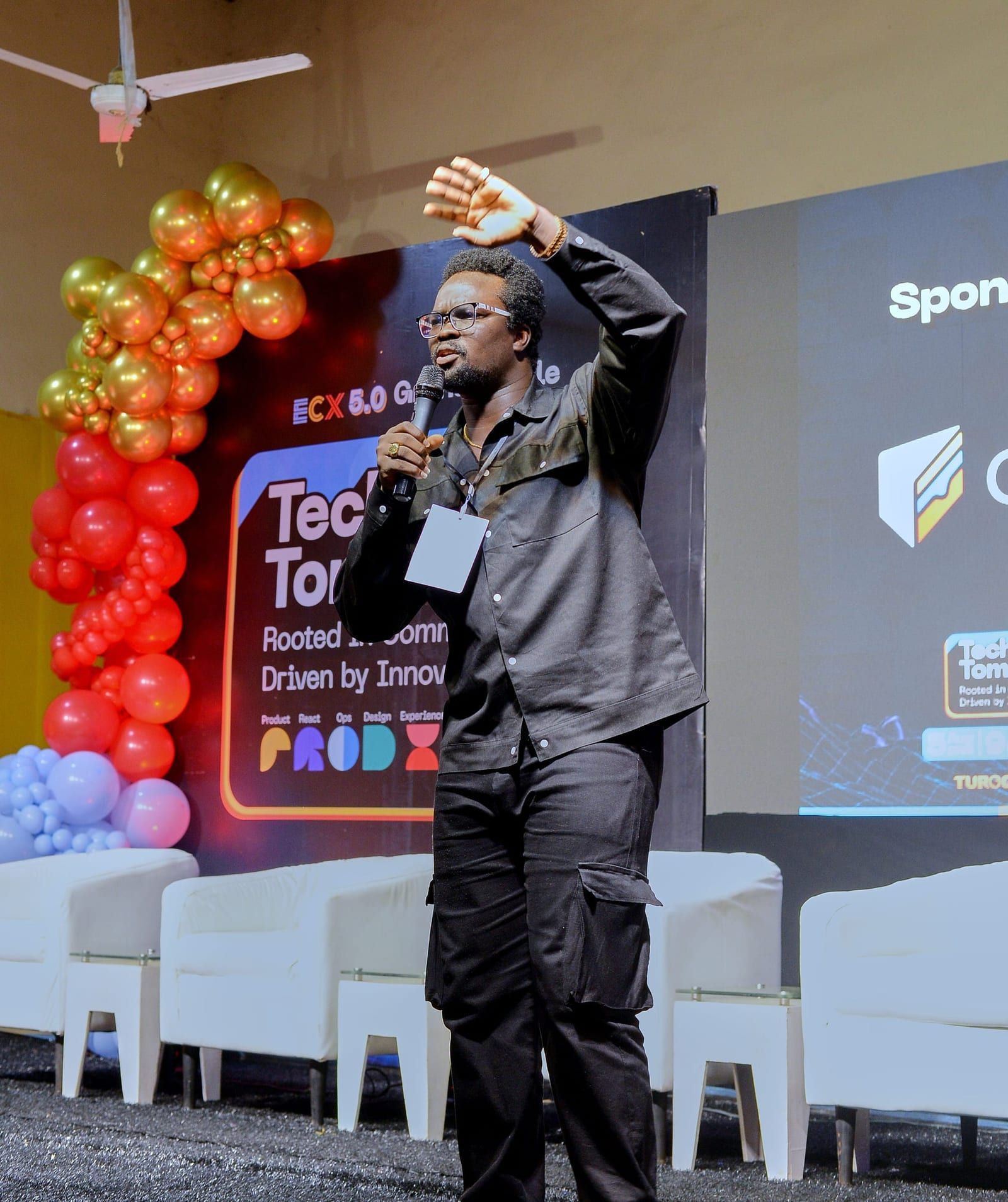 David on stage with an arm over his head, the ECX 5.0 Grand Finale backdrop and a balloon arch behind him.