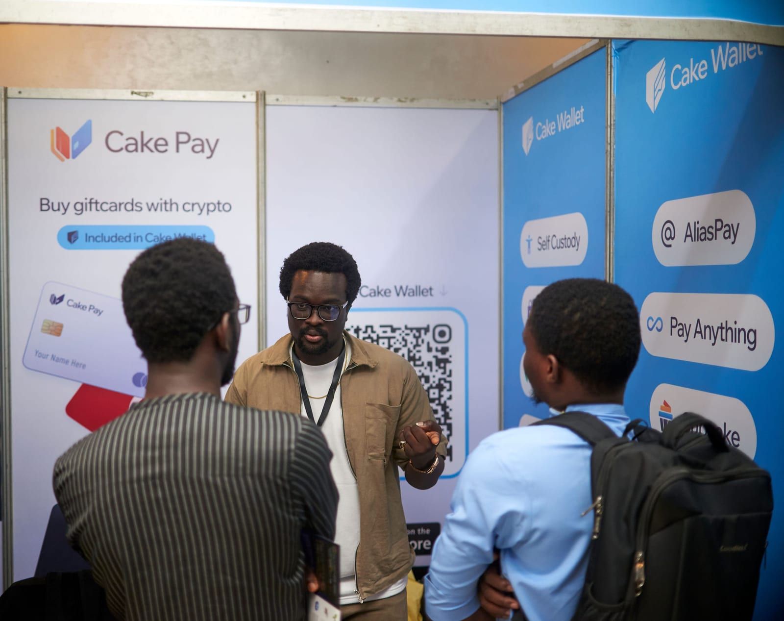 David mid-explanation at the Cake Pay and Cake Wallet booth with two attendees.