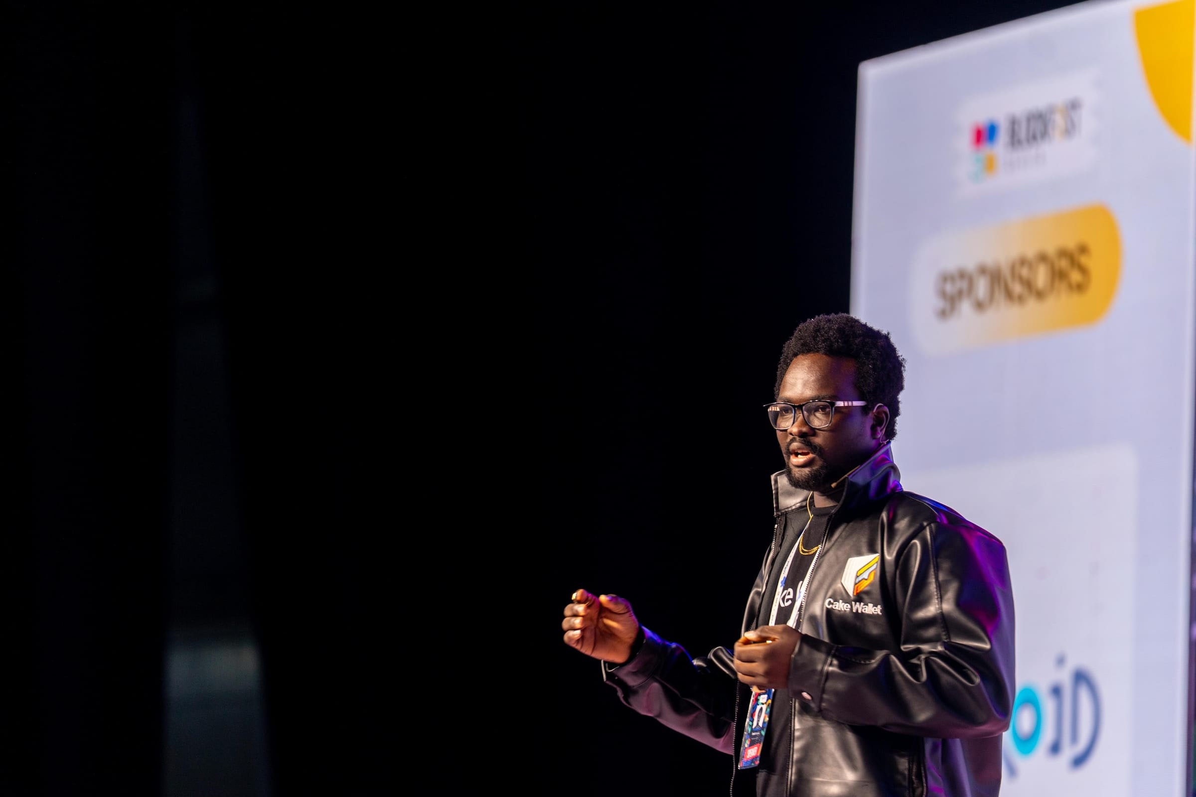 David Adegoke speaking on the Blockfest Africa 2025 stage in a Cake Wallet jacket.